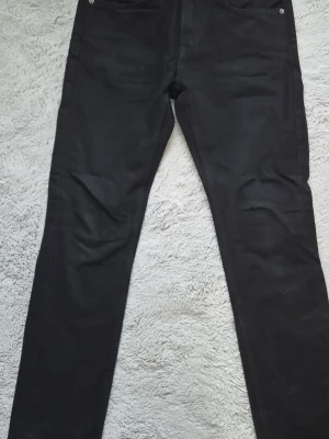 Svarta jeans - Säljer ett par svarta jeans med rak passform . Jeansen har normal midja och är tillverkade i ett slitstarkt denimtyg. Perfekta för dig som gillar en enkel och stilren look.  Storlek 28 32 använd 2 gånger