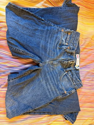 Levi's raka blå jeans - Klassiska blå Levi's jeans med slim taper i passform och fem fickor. Jeansen har tydliga sömmar, bälteshällor och Levi's ikoniska läderpatch bak i midjan. Tillverkade i slitstark denim med en snygg tvättad look.