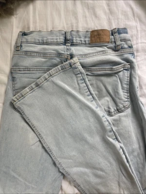 Ljusblå bootcut jeans  - Säljer ett par ljusblå jeans med bootcut passform och klassisk femficksdesign. Jeansen har bälteshällor, knappgylf och är tillverkade i mjukt denimtyg. Perfekta för en avslappnad och trendig look.