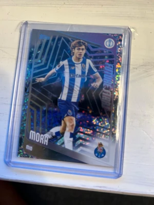 Rodrigo Mora topps kort numererad /10 - Rodrigo Mora fotbollskort från Topps. Kortet är numrerat 04/10 och föreställer Rodrigo Mora i FC Porto-tröja. Han är mittfältare och beskrivs som en spelfördelare med förmåga att leverera bollen till sina lagkamrater. Efter en säsong med imponerande prestationer i klubbens juniorlag, blev han uttagen till FC Portos UEFA Champions League-trupp för säsongen 2024/25.  Potensiellt psa 10 värde då den åkte i sleeven o toploader direkt efter öppning