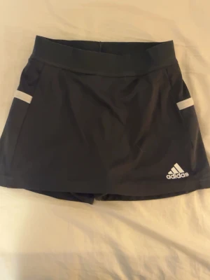 Svart tennis/paddelkjol från adidas - En super gullig tennis/paddel kjol från adidas. Kjolen är ganska liten i storlek så den är snarare XXS/XS än M.