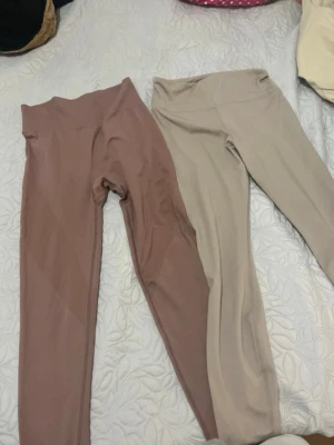 Två par leggings i beige och brunrosa - Säljer två par leggings i mjukt stretchigt material. Ena paret är beige och det andra är brunrosa. Båda har hög midja och smal passform, perfekta för en avslappnad och trendig look.