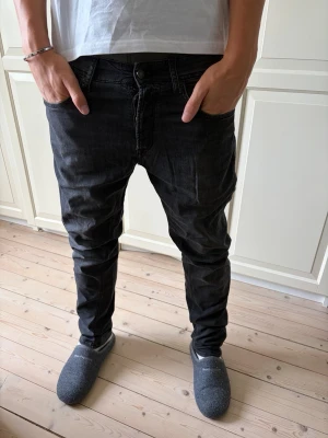 Svarta Replay slim fit jeans  - Säljer ett par svarta slim fit jeans med låg midja och klassisk femficksmodell. Jeansen har en något tvättad look och smala ben. Passar perfekt till en avslappnad stil. Har ett litet hål vid höger bakficka som syns på bilden. Jeansen har storlek 30/32 och är modellen grover. Hör av er vid frågor och priset är inte hugget i sten!