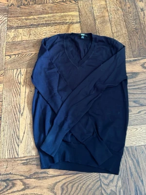 Mörkblå tröja från Uniqlo - Snygg mörkblå  tröja från Uniqlo med V-ringning. 🤍Tröjan har långa ärmar och ribbade muddar vid ärmslut och nederkant. Perfekt att bära över en skjorta eller t-shirt för en clean och enkel look. Nästan ingen användning och helt ny❣️
