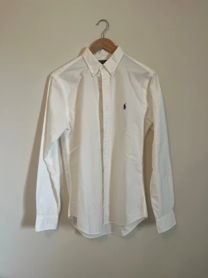 Oanvänd - vit Ralph Lauren oxfordskjorta - Klassisk vit Ralph Lauren-skjorta i oxford med button-down krage i storlek S och slim fit. Köpt på Care of Carl, men aldrig använt då den var för liten för mig. 