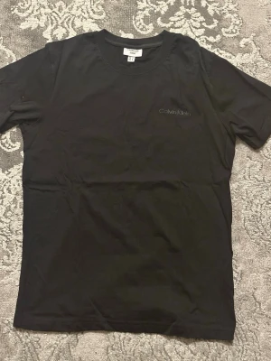 Calvin Klein T-shirt  - En stilren svart Calvin Klein t-shirt med diskret logga på bröstet använd en gång. Klassisk rund halsringning och korta ärmar. Perfekt till jeans eller shorts för en clean o stilren look, pris kan diskuteras vid snabb affär.