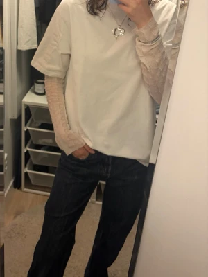 Vit mesh topp med strukturmönster - Säljer en vit långärmad mesh topp med diskret strukturmönster och lätt transparent material. Toppen har en mjuk, vågig kant vid halsen och är perfekt för att styla i lager på lager. Jag har klippt armarnas längd och toppens längd då den var väldigt lång (se bilder) 💖💖Från gina men jag har klippt av lappen