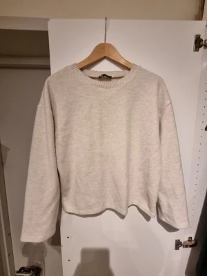 Beige sweatshirt från Zara - En enkel och stilren beige sweatshirt från Zara med rund halsringning och ribbade muddar. Tröjan har en avslappnad passform och är perfekt för en chill look. Tillverkad i mjukt material som känns skönt mot huden.