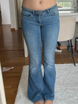 Ljusblå bootcut jeans - Säljer ett par ljusblå bootcut jeans med låg midja. Stretchiga och sköna från Vero Moda i storlek S längd 34💕De är lite slitna längst ner vid baksidan av benen då de är lite långa på mig och jag har trampat på dem- det är dock inget man tänker på när man har dem på sig