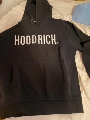 Svarta mjukisbyxor från Hoodrich - Säljer ett par svarta mjukisbyxor från Hoodrich med loggan broderad i vitt på ena benet. Byxorna har resår i midjan och är gjorda i mjukt sweatshirtmaterial. Perfekta för en chill och avslappnad stil. Med byxorna förljer även en hoodie med