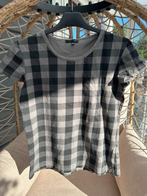 T-shirt strl. 38/40 - Rutig t-shirt från by Ellos i svart och grått. Klassisk rund halsringning och korta ärmar. Tillverkad i mjuk bomull som känns skön mot huden. 