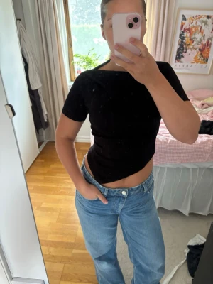 Svart snedskuren topp - Säljer en svart croppad topp med korta ärmar och rund hals. Toppen har en tight passform och är snedskuren nedtill. Oanvänd med prislappen kvar!💞