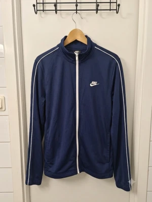 Klassisk Nike Track Jacket / Träningsjacka – Mörkblå – Stl L 💙🔥 - Klassisk och tidlös träningsjacka från Nike i mörkblått med vita kontrastdetaljer. Skön passform med full dragkedja, sidofickor och Nike-logga på bröstet. I mycket gott begagnat skick och välvårdad! Skickas snabbt. 📦✨