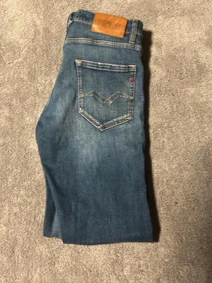 Blå slim tapered jeans Replay -  Kan diskutera pris vid snabb affär Snygga blå jeans från Replay i modellen slim tapered fit. Jeansen har klassisk femficksdesign, ljus tvätt och detaljerade sömmar på bakfickan. Perfekta för dig som gillar en smalare passform och stilren look.