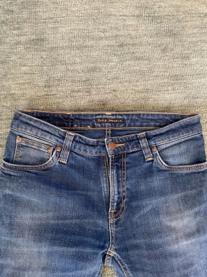 Nudie Jeans - Snygga klassiska jeans från Nudie Jeans Co. i mörkblå denim. Modellen har en smal/slimmad passform med lätt tvättade detaljer som ger en snygg, använd look.