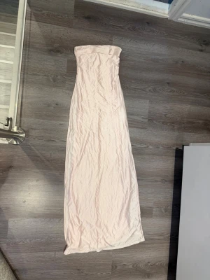 Ljusrosa långklänning från Ginatricot  - Säljer en elegant ljusrosa långklänning i ett slätt, mjukt tyg. 
