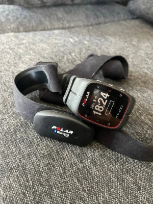 Polar M400 smartklocka med pulsbälte - Polar M400 smartklocka i svart med fyrkantig display och röda detaljer. Medföljer matchande pulsbälte med Bluetooth-funktion. Perfekt för träning och aktivitetsmätning. Klockan har silikonarmband och tydlig digital skärm.
