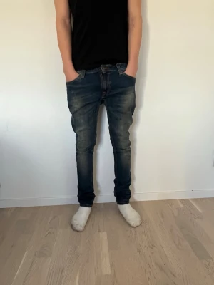 Mörkblå nudie jeans  - Lite för små på mig storlek 32/32 Säljer ett par mörkblå slim fit jeans med snygg slitning och tvättade detaljer. Jeansen har klassisk femficksdesign, normal midja och smala ben. Perfekta för en avslappnad och trendig stil.