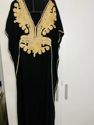 Kaftan fårn Marocko - Säljer en jättefin svart kaftan/klänning som jag köpte när jag var i Marocko. Jag köpte den själv där och den har ett jättefint guldmönster framtill som verkligen gör den lite extra fin och elegant. Den har även en knytning pà insidan vid midjan sả att man kan knyta den och fă den att sitta finare efter sin egen kropp. Passar ungefär XXS, XS och S beroende pà hur man vill att den ska sitta. Perfekt om man vill ha nägot lite extra fint till exempelvis fest, middag eller nägot speciellt tillfälle.
