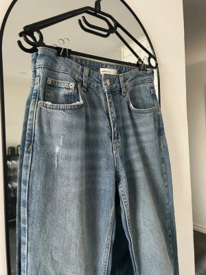 Blåa jeans - Utsvängda blåa jeans med ett hål på ena benet från gina tricot i mycket bra skick, skulle säga att dom sitter ”mellan” i midjan. 💕