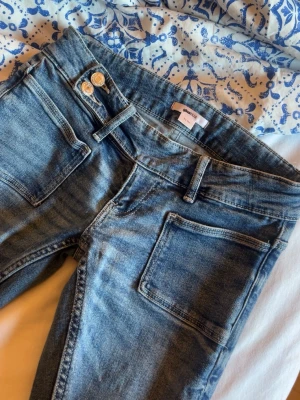 Blå jeans - Säljer ett par klassiska blå jeans med snygg tvätt. Jeansen har två framfickor, två bakfickor och dubbla silverknappar i midjan. Materialet är mjukt denim som sitter skönt och passar till det mesta.