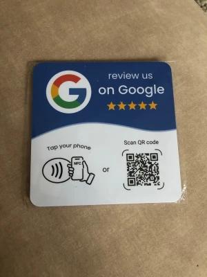 Google recension-bricka med NFC & QR - Praktisk fyrkantig bricka för att samla Google-recensioner. Ena sidan har Google-logga, text och QR-kod, samt NFC-symbol för mobil. Baksidan har självhäftande 3M-tejp för enkel montering. Perfekt för företag som vill få fler recensioner.