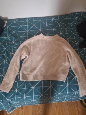 Beige stickad tröja från FB Sister - Mysig beige stickad tröja från FB Sister i ribbstickat material. Tröjan har en rak passform, långa ärmar och ribbade muddar vid ärmslut och nederkant. Perfekt för lager på lager och enkel att matcha med olika outfits.