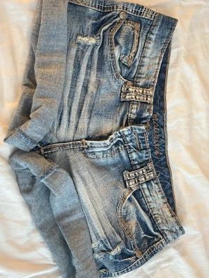 Blå jeans shorts  - Säljer ett par blå jeans shorts med slitna detaljer och uppvikta benslut. Köpta i Malmö på second hand för 500kr