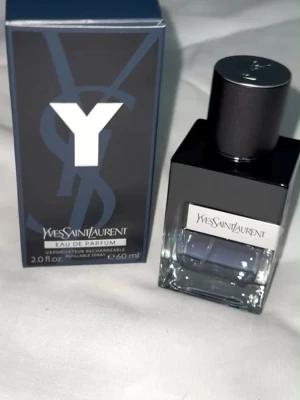 Yves Saint Laurent Y Eau de Parfum - Y Eau de Parfum från Yves Saint Laurent är en elegant herrdoft i en stilren glasflaska med svart lock och silverdetaljer. Flaskan rymmer 60 ml och har en modern, maskulin design med märkets logga tydligt på både kartong och flaska.