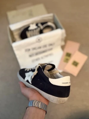 Golden Goose svarta sneakers med stjärna - Snygga mörkblå sneakers från Golden Goose med vit stjärndetalj på sidan och vit hälkappa. Skorna har vita skosnören och en slitstark sula. Ovandelen är i mocka och detaljerna i läder. 