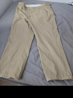 Beiga chinos från L.L. Bean - Klassiska beiga chinos från L.L. Bean med rak passform och diskreta fickor. Tillverkade i ett mjukt och slitstarkt bomullstyg som ger en clean och avslappnad look. Perfekta för dig som gillar tidlös och enkel stil.