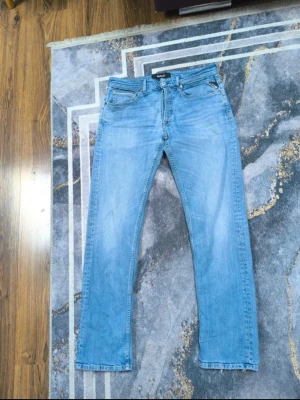 Ljusblå reaplay jeans - Säljer ett par ljusblå jeans med bra passform och klassisk femficksdesign. Jeansen har bälteshällor, knappgylf och subtila slitningar för en avslappnad look. Perfekta till vardagsstilen