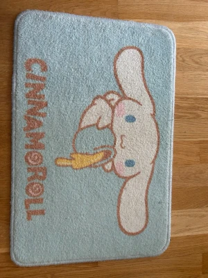 Cinnamoroll  matta - Söt ljusblå matta med Cinnamoroll-motiv och text. Mattan har en rektangulär form, mjuk yta och halkskydd på undersidan. Perfekt för att ge rummet en gullig touch. Motiv i vitt, blått, rosa och gult. Köpt i Miniso i Amsterdam för typ 400kr