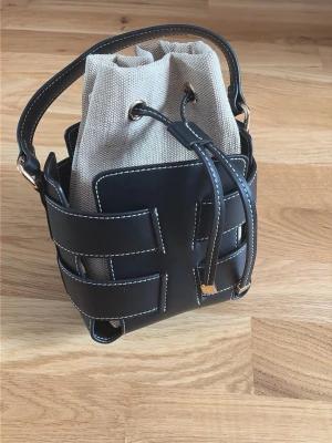 Svart bucket bag - Säljer denna otroliga och identiska dupen på den virala väskan från hm. Bandet tillkommer! Den är oanvänd. Pris går att diskuteras ☺️