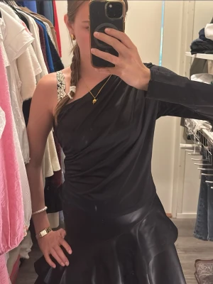 Svart oneshoulder topp - Snygg svart oneshoulder topp från hm med lång ärm på ena sidan och bar axel på andra. Toppens material är mjukt och stretchigt, vilket ger en smickrande passform. Perfekt till mer speciella tillfällen eller om man bara vill sticka ut