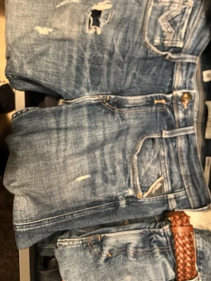 Blå slitna jeans med hål - Replay jeans modell anbass, naturlig fade och slitningar. storlek 29/32. Hör av dig om du har funderingar eller vill se dom på. Skickar dom samma dag som köpet går igenom. 