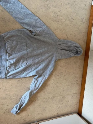 Hoodie - Jag säljer en grå hoodie i storlek 164. Hoodien är i mycket bra skick, sparsamt använd och utan några synliga defekter som fläckar eller hål. Den är tillverkad i ett mjukt och skönt bomullsmaterial, vilket gör den perfekt för både vardagsbruk och sportaktiviteter.          Priset är 60 kr, vilket är ett fynd med tanke på skicket! Nypris för en liknande hoodie ligger runt 300 kr.                         Är du intresserad eller har några frågor? Tveka inte att kontakta mig!