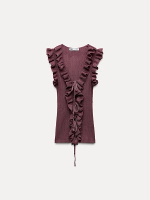 Lila ribbad topp med volang och snörning - Supersnygg lila ribbad topp med djup v-ringning, volangdetaljer längs kanterna och snörning framtill. Ärmlös modell som ger en trendig och feminin look. Perfekt att styla med jeans eller kjol för en cool vibe.