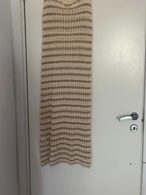 Randig långklänning i stickad bomull - Säljer en lång stickad klänning med breda ränder i beige och olivgrönt. Klänningen har v-ringning och är ärmlös, perfekt för varma dagar och till stranden. Materialet är mjuk bomull och modellen är loose fit för en avslappnad look. Storlek är i XS/S både två.