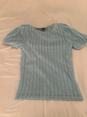 Ljusblå spetsblus med puffärm.str 10 - Supersöt ljusblå blus med korta puffärmar och spetsdetaljer i hela tyget. Blusen har rund halsringning och är lätt transparent med ett mjukt innerfoder. Perfekt för dig som gillar romantiska och feminina toppar.