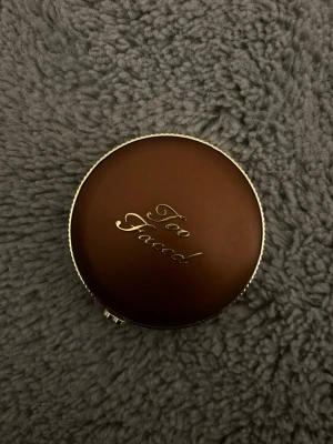 Too Faced bronzer  - Ordinarie pris på 470. Snygg bronzer från Too Faced i en rund, brun kompakt dosa med guldfärgad logga på locket. Perfekt för att ge ansiktet en solkysst look och snygg lyster. Dosan är smidig att ha med i väskan och har en lyxig känsla.