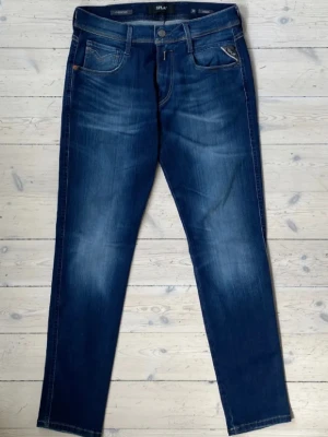 Mörkblå jeans från REPLAY - Snygga mörkblå jeans från replay med klassisk femficksmodell och diskreta slitningar framtill. Jeansen har raka ben och kontrastsömmar som ger en stilren look. Perfekta till en avslappnad outfit och passar till det mesta. 30/32