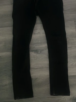 Svarta skinny jeans - Säljer ett par svarta skinny jeans med smal passform och klassisk femficksdesign. Jeansen har hög midja och är tillverkade i stretchigt material för extra komfort. Perfekta till en avslappnad eller trendig look. 34 midjan 32 längd 