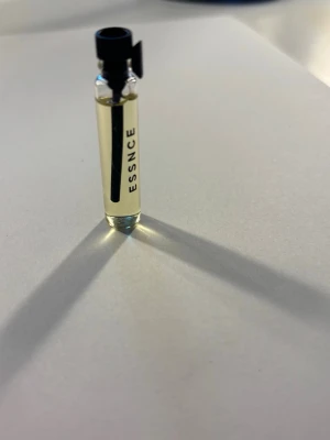 Essnce tester fizzy mango - En liten genomskinlig glasflaska med svart kork och texten ESSNCE på sidan. Det är doften fizzy mango. Flaskan innehåller en ljusgul parfymvätska och är perfekt som prov eller för resan. Enkel och stilren design 💛🥭