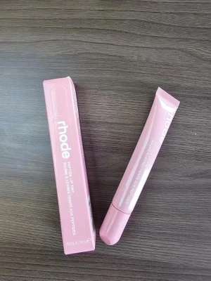Rhode Peptide Lip Tint ribbon - Rhode Peptide Lip Tint i en snygg rosa tub med matchande förpackning. Läppbalsamet har en mjuk applikator och ger en subtil rosa ton till läpparna. Tuben rymmer 10 ml och har en modern, minimalistisk design.