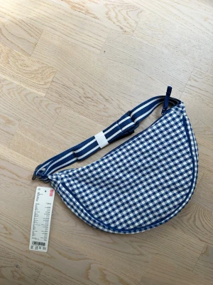 Uniqlo gingham round mini shoulder bag - Easy and stylish bag, you can put in surprisingly a lot! Has inner pockets and zip to keep everything secure. Lovely fresh design and super durable quality!  From the website:  Compact design with surprising storage capacity.  Seersucker fabric with gingham check added for a fresh design.  The water-repellent finish protects against light rain. *The finish is not permanent.  Size Width(Top): 28cm, Height: 17cm, Depth: 10cm, Shoulder Strap Length: 62cm~116cm, Bag Capacity: 4Liters   #uniqlo
