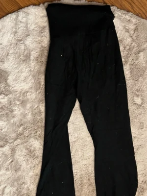 Svarta ribbade leggings med hög midja - Säljer ett par svarta yoga pants med mellan midja och ribbad linning. De har en enkel, stilren design och är tillverkade i ett stretchigt material som sitter skönt på kroppen. Perfekta för en avslappnad och trendig look.