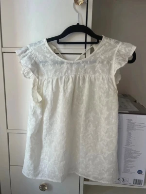🤍 Vero Moda vit blus med volangärmar & broderier | XS - Säljer en superfin vit blus från Vero Moda i storlek XS. Blusen har vackra broderidetaljer och fina volangärmar som ger en feminin och romantisk look. Perfekt till jeans, kjol eller kostymbyxor – passar både till vardag och fest.