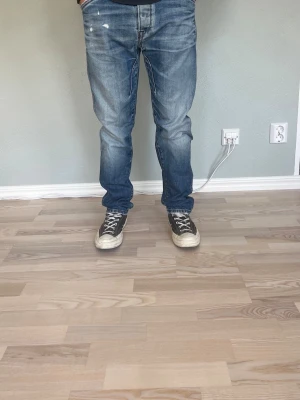 Jack & Jones Originals Erik Anti Fit W31 L32 – Vintage fade | Mörkblå - JACK & JONES ORIGINALS — ERIK ANTI FIT  Storlek: W31 L32 Passform: Anti Fit — avslappnat och generöst sitt utan att vara baggy Färg: Mediumblå med naturlig vintage fade Kollektion: Originals by Jack & Jones  Anti Fit är en av J&J:s mer eftertraktade passformar — rak och avslappnad med lite extra utrymme i lår och höft. Naturlig fading och whiskering som ger dem karaktär.  Modellen på bilden är 175 cm och väger 65 kg — jeansen sitter avslappnat och modernt.  Skick: Bra skick. Små slitningar enlig