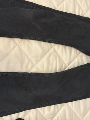 Svarta bootcut jeans - Säljer ett par svarta bootcut jeans med klassisk femficksmodell och dragkedja. Jeansen har en lätt utsvängd passform nedtill och är tillverkade i ett mjukt denimtyg. Säljer dom för en billig penga. Slutade använda dom efter jag köpte ett nya svarta jeans annars inget fel på dom. Lite slitna mellan benen. 